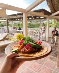 a person holding a plate of food on a table at Hotel Flor de Maria - Adults Only in Puerto Escondido +35 photos