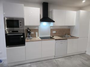 a white kitchen with white cabinets and a microwave at Domaine de Zely in Fontaines-dʼOzillac