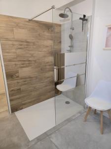 a shower with a glass door and a white chair at Domaine de Zely in Fontaines-dʼOzillac