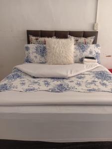 a bed with blue and white sheets and pillows at Happy Guest House in Mahikeng