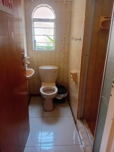 a small bathroom with a toilet and a window at Happy Guest House in Mahikeng