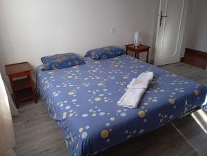 a bed with a blue comforter with a towel on it at La maison de J et B étage entier in Tarbes +10 photos