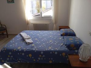 a bedroom with a bed with a blue comforter and a window at La maison de J et B étage entier in Tarbes