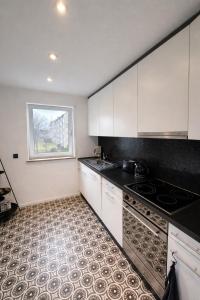 eine leere Küche mit weißen Schränken und einem Fenster in der Unterkunft Modernes Dachgeschossapartment in Singen Zentrum in Singen