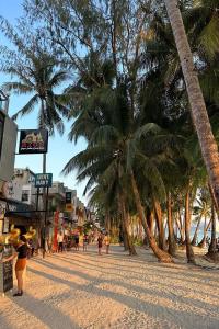 a beach with palm trees and people walking on a sidewalk at Lazy Daze Hometel Boracay in Boracay