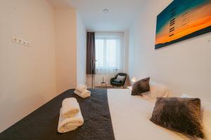 a bedroom with a large white bed with a chair at Riverline Apartman in Odorheiu Secuiesc +45 photos