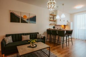 a living room with a green couch and a kitchen at Riverline Apartman in Odorheiu Secuiesc