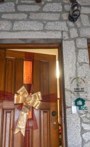 a door with a bow on a stone wall at Casa do Palheiro in Campo do Gerês
