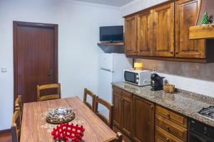 a kitchen with a wooden table and a microwave at Casa do Palheiro in Campo do Gerês
