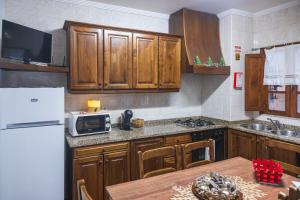 a kitchen with wooden cabinets and a table with a microwave at Casa do Palheiro in Campo do Gerês +31 photos