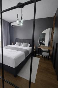 a bedroom with a large bed and a desk at Urban Forest Apartment - with free Garage in Podgorica