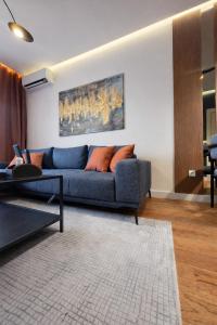 a living room with a blue couch with orange pillows at Urban Forest Apartment - with free Garage in Podgorica