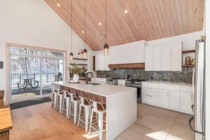 a kitchen with white cabinets and a large island with bar stools at 32 Chemin Blanc in Stoneham