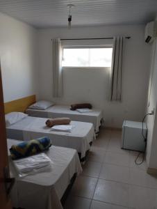 a room with three beds and a window at Pousada Nascimento in Trindade
