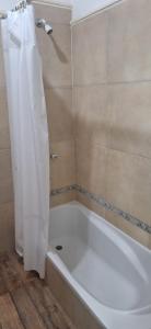 a white bath tub with a shower curtain in a bathroom at Victoriano in La Rioja +16 photos