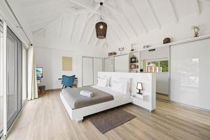 a white bedroom with a bed and a blue chair at Villa Angel Sunset in Gustavia +18 photos