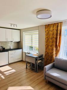 a kitchen and living room with a table and a couch at White Sun Apartment in Aizkraukle