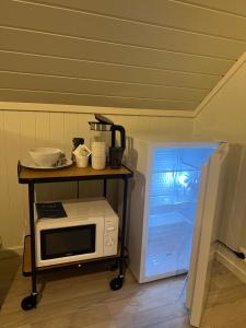 a microwave on a cart next to a refrigerator at Lofoten - Spacious Room in Vestvågøya
