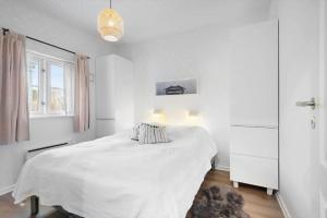 a white bedroom with a bed and a window at BV435-Blavand-Horns-Bjerge-3-59 in Blåvand