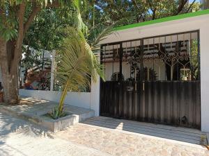 a house with a black gate and a palm tree at Esperanza Casa de Huéspedes in Brisas de Zicatela +2 photos