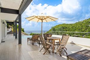 a patio with a table and chairs and an umbrella at Villa Angel Sunset in Gustavia