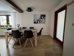 a dining room with a table and black chairs at Ferienhaus Kluttig in Hörnitz +8 photos