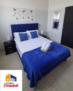 a bedroom with a large bed with a blue headboard at HOTEL CONSULADO Junto al Consulado de Venezuela in Cúcuta