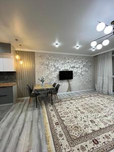 a dining room with a table and a tv on a wall at ЖК City plus Евродвушка in Almaty
