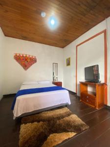 a bedroom with a bed and a flat screen tv at Hostal Arraigo - A 1 calle del Parque Principal in Santa Rosa de Cabal