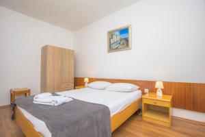 a bedroom with a bed with white sheets and pillows at Apartmani Jurin in Primošten