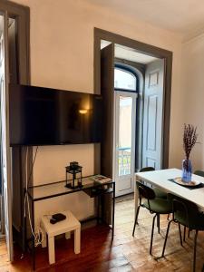 a living room with a table and a television on a wall at Spacious T4 Central Apartment with Iconic Tram 28 View in Lisbon