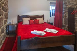a bedroom with a red bed with towels on it at Casa da Cuca in Campo do Gerês