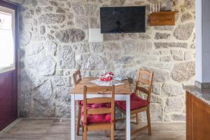 a dining room table with chairs and a stone wall at Casa da Cuca in Campo do Gerês