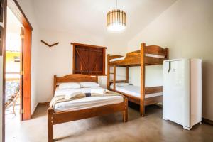 a bedroom with two bunk beds and a refrigerator at Pousada das Estrelas in Itaúnas