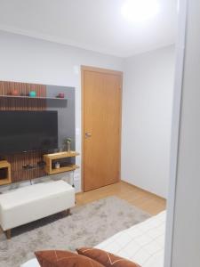 a living room with a television and a door at Juhh Bella in Botucatu
