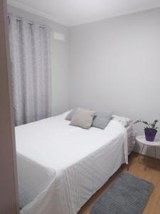 a bedroom with a white bed and a table at Juhh Bella in Botucatu
