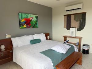 a bedroom with a bed and a painting on the wall at Hotel Las Lomas in Nandayure