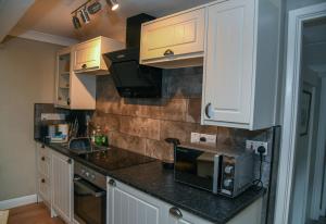 a kitchen with white cabinets and a black counter top at No6 @ Globe Lane,Alston in Alston