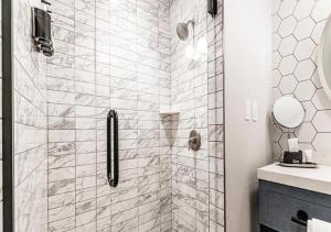 a bathroom with a walk in shower with white tiles at Oak Grove Racing Gaming & Hotel in Oak Grove