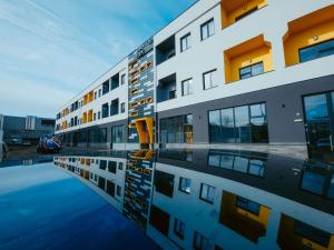 a building with its reflection in a pool of water at Riverline Apartman in Odorheiu Secuiesc