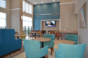 a waiting room with tables and chairs and a tv at Hampton Inn & Suites by Hilton Tomball Houston NW in Tomball
