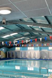 a swimming pool with red and blue flags on the ceiling at The Three bs in Scratby