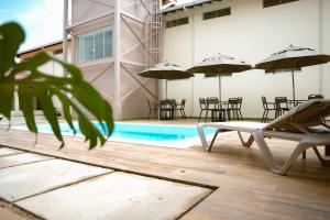 a pool with chairs and umbrellas next to a building at Hotel Equinócios Express in Barcarena