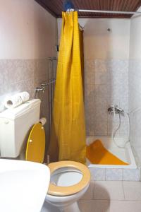 a bathroom with a toilet and a yellow shower curtain at Casa dos Cobertos in Terras de Bouro +25 photos