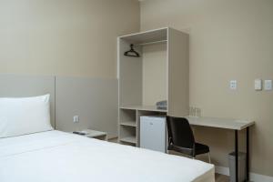 a bedroom with a bed and a desk and a chair at Hotel Equinócios Express in Barcarena