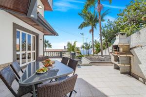 a patio with a table and chairs and a grill at Cumbres Villa in Funchal