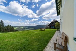 a bench sitting on the side of a building with a grass field at Ferienwohnungen Hebalm in Pack