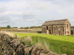 Eine alte Steinscheune auf einem Feld mit einer Steinmauer in der Unterkunft Riber View Barn in Chesterfield