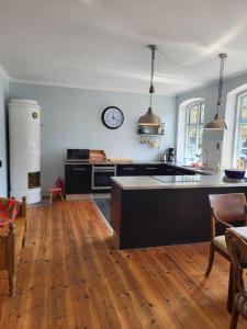 a kitchen with wooden floors and a clock on the wall at Inseldomizil Brummers Gaard in Haderslev