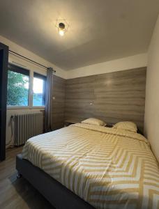 a bedroom with a bed with a striped comforter and a window at les gîtes de la Colombière 10 personnes in Longvic